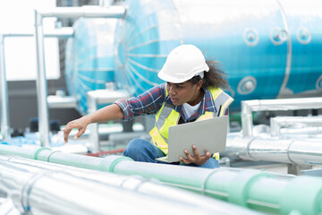 Female engineer working with laptop computer for checks or maintenance in sewer pipes area at...