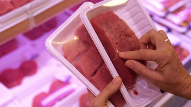 The customer selects fresh meat to prepare a delicious meal. High quality meat cut into portions in the form of steaks and laid out in plastic packaging for portions for cooking.