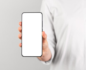 Woman holding phone mockup in vertical position. Female using smartphone for showing photo or...