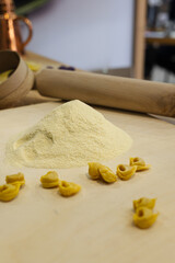 Freshly Made Raw Tortellini over Wooden Table and a Rolling Pin and Flour in the Background