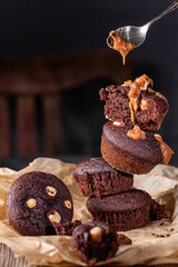 A pile of brownie muffins with liquid caramel falling from a spoon.