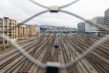 Blick auf die Geleise des Hauptbahnhofs in Zürich, ein Zug im Zentrum der Symmetrie und der...