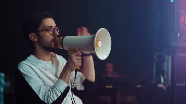 A male director on the set shouts into a megaphone to the actors