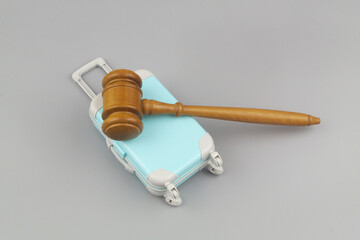Legal support on travel trip concept. Suitcase with wooden judge gavel on gray background.