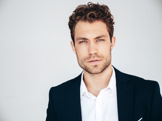 Portrait of handsome confident  stylish hipster lambersexual model. Sexy modern man dressed in black elegant suit. Fashion male posing in studio on white background