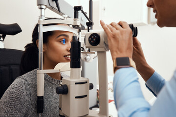 Eye test, exam or screening with an ophthalmoscope and an optometrist or optician in the optometry industry. Young woman getting her eyes tested for prescription glasses or contact lenses for vision - Powered by Adobe