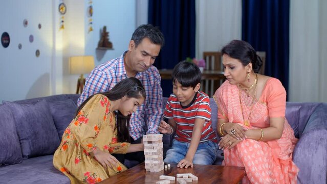 A middle-aged couple and their kids playing with building blocks - happy parenting  family time  Indian family . A cheerful Gujarati family - Father  mother and kids  nuclear Indian family  kids pl...