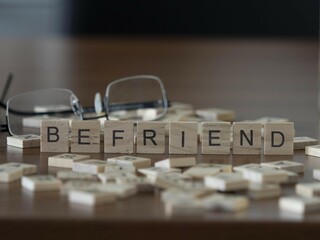befriend word or concept represented by wooden letter tiles on a wooden table with glasses and a...