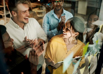 Successful business team clapping and cheering after planning a project on a glass wall in a...