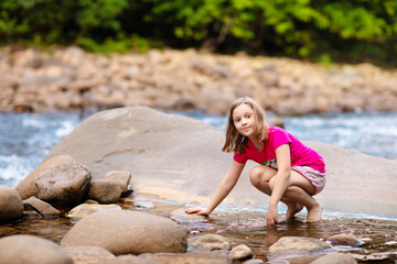 Child hiking in mountains. Kids at river shore.
