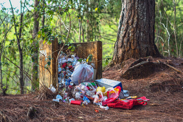 Dump in forest summer park. Overflowing concrete trash can. No control take out landfill garbage....