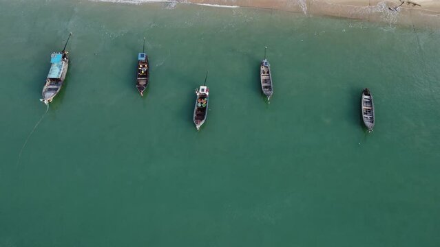 Aerial view from drones of fishing boats in the shore during low tide. Top view of many Thai traditional longtail fishing boats in the tropical islands. A lot of long tail boat on sea