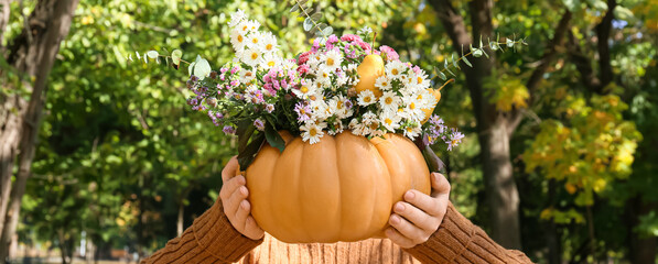 Woman holding beautiful bouquet of autumn flowers in pumpkin outdoors