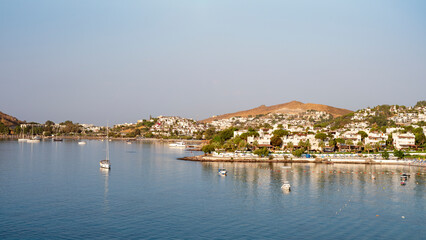 Fototapeta na wymiar View of Bodrum Beach, Aegean sea, traditional white houses, flowers, marina, sailing boats, yachts in Bodrum town Turkey. Front view