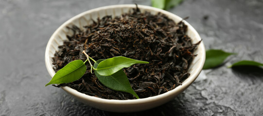 Bowl with dry tea leaves on table, closeup