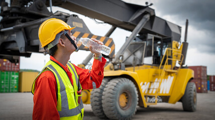 Foreman or worker is drinking a bottle of water after finishing work and relaxing on the old truck...