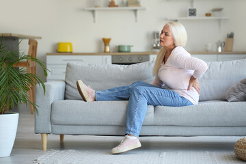Obraz premium Mature woman suffering from back pain in kitchen