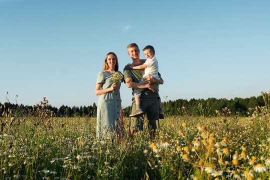 Mother, Father And Son Squint From The Sun In The Field