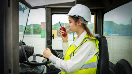 Female Foreman Drive a forklift container cargo forklift and use walkie talkie for communication...