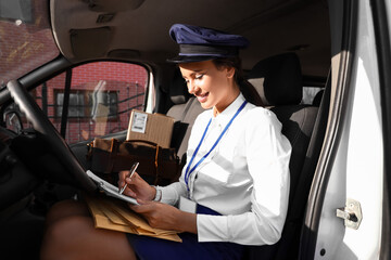 Beautiful postwoman with clipboard in car