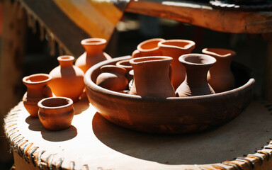 Simple homemade clay crafts, jugs and cups outdoors on a sunny day. Close-up, selective focus