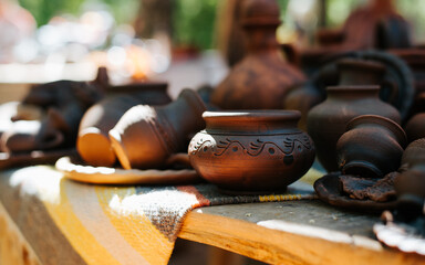 Medieval pottery, close-up of decorated clay cups and plates on a table outdoors. Selective focus