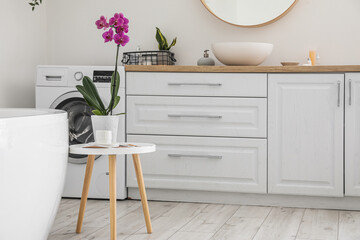 Orchid flower, cup of coffee and magazine on table in bathroom interior