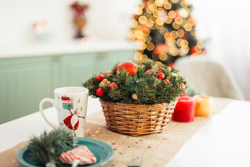 Table is Festively Set for Christmas. Red Candles and Christmas Tree Arrangement in Wicker Basket