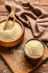 Board with bowls of sesame seeds on wooden table, closeup