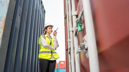 Woman foreman smile using walkie talkie in front of Cargo forklift in warehouse , Manager in white helmet Safety Supervisor in Container Custom Terminal port concept import export