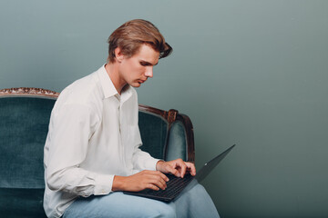 Portrait european young man sitting with laptop at studio