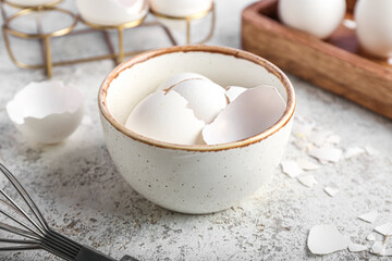 Bowl with broken egg shells on grunge background, closeup