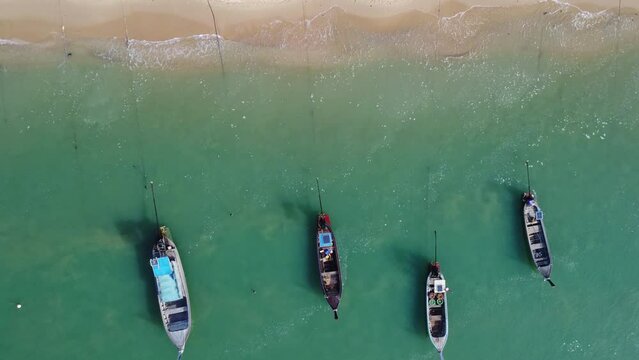 Aerial view from drones of fishing boats in the shore during low tide. Top view of many Thai traditional longtail fishing boats in the tropical islands. Pier of the villagers on the southern island of