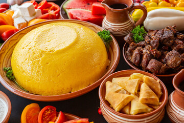 Homemade Romanian Food with polenta, meat, cheese and vegetables. Delicious corn porridge in clay dishes. Mamaliga or polenta, a traditional dish in Moldova, Hungary and Ukrainian cuisine.
