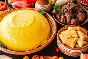 Homemade Romanian Food with polenta, meat, cheese and vegetables. Delicious corn porridge in clay dishes. Mamaliga or polenta, a traditional dish in Moldova, Hungary and Ukrainian cuisine.
