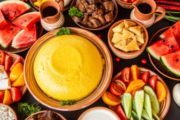 Homemade Romanian Food with polenta, meat, cheese and vegetables. Delicious corn porridge in clay dishes. Mamaliga or polenta, a traditional dish in Moldova, Hungary and Ukrainian cuisine.
