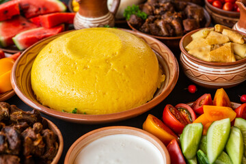 Homemade Romanian Food with polenta, meat, cheese and vegetables. Delicious corn porridge in clay dishes. Mamaliga or polenta, a traditional dish in Moldova, Hungary and Ukrainian cuisine.
