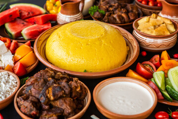 Homemade Romanian Food with polenta, meat, cheese and vegetables. Delicious corn porridge in clay dishes. Mamaliga or polenta, a traditional dish in Moldova, Hungary and Ukrainian cuisine.
