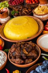Homemade Romanian Food with polenta, meat, cheese and vegetables. Delicious corn porridge in clay dishes. Mamaliga or polenta, a traditional dish in Moldova, Hungary and Ukrainian cuisine.
