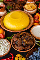 Homemade Romanian Food with polenta, meat, cheese and vegetables. Delicious corn porridge in clay dishes. Mamaliga or polenta, a traditional dish in Moldova, Hungary and Ukrainian cuisine.
