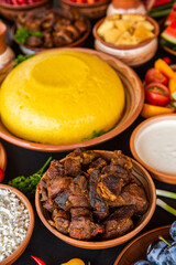 Homemade Romanian Food with polenta, meat, cheese and vegetables. Delicious corn porridge in clay dishes. Mamaliga or polenta, a traditional dish in Moldova, Hungary and Ukrainian cuisine.
