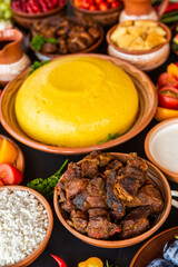 Homemade Romanian Food with polenta, meat, cheese and vegetables. Delicious corn porridge in clay dishes. Mamaliga or polenta, a traditional dish in Moldova, Hungary and Ukrainian cuisine.
