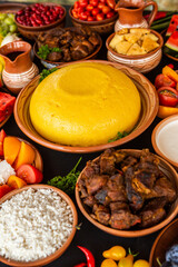 Homemade Romanian Food with polenta, meat, cheese and vegetables. Delicious corn porridge in clay dishes. Mamaliga or polenta, a traditional dish in Moldova, Hungary and Ukrainian cuisine.

