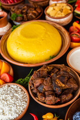 Homemade Romanian Food with polenta, meat, cheese and vegetables. Delicious corn porridge in clay dishes. Mamaliga or polenta, a traditional dish in Moldova, Hungary and Ukrainian cuisine.
