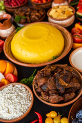 Homemade Romanian Food with polenta, meat, cheese and vegetables. Delicious corn porridge in clay dishes. Mamaliga or polenta, a traditional dish in Moldova, Hungary and Ukrainian cuisine.
