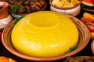 Homemade Romanian Food with polenta, meat, cheese and vegetables. Delicious corn porridge in clay dishes. Mamaliga or polenta, a traditional dish in Moldova, Hungary and Ukrainian cuisine.
