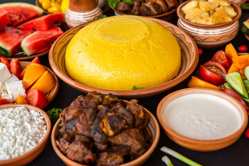 Homemade Romanian Food with polenta, meat, cheese and vegetables. Delicious corn porridge in clay dishes. Mamaliga or polenta, a traditional dish in Moldova, Hungary and Ukrainian cuisine.
