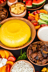 Homemade Romanian Food with polenta, meat, cheese and vegetables. Delicious corn porridge in clay dishes. Mamaliga or polenta, a traditional dish in Moldova, Hungary and Ukrainian cuisine.
