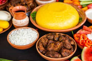 Homemade Romanian Food with polenta, meat, cheese and vegetables. Delicious corn porridge in clay dishes. Mamaliga or polenta, a traditional dish in Moldova, Hungary and Ukrainian cuisine.
