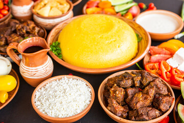Homemade Romanian Food with polenta, meat, cheese and vegetables. Delicious corn porridge in clay dishes. Mamaliga or polenta, a traditional dish in Moldova, Hungary and Ukrainian cuisine.
